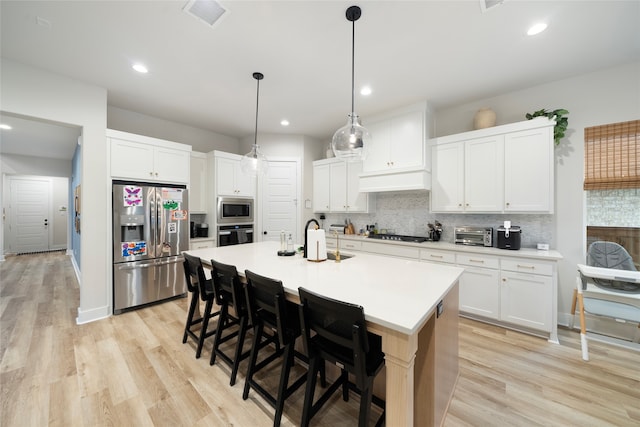 kitchen featuring stainless steel appliances, light hardwood / wood-style floors, and white cabinets