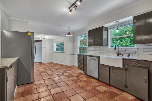 kitchen with tasteful backsplash, crown molding, appliances with stainless steel finishes, decorative light fixtures, and sink