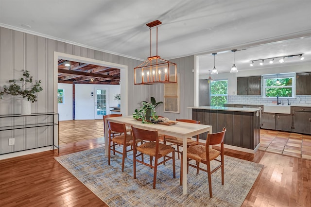 dining area with light hardwood / wood-style floors, sink, crown molding, and a notable chandelier