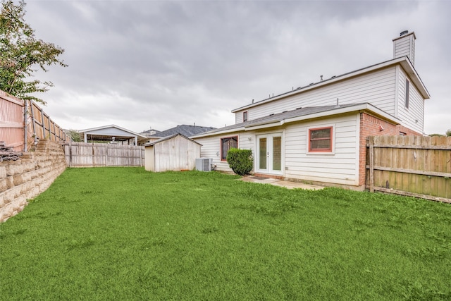 rear view of property with central air condition unit and a yard