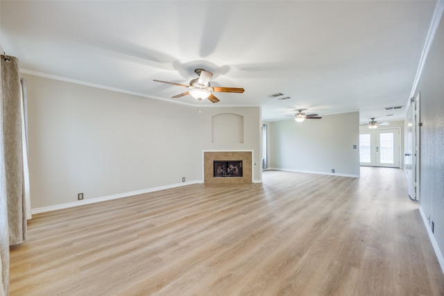 unfurnished living room with french doors, a fireplace, light hardwood / wood-style floors, and crown molding