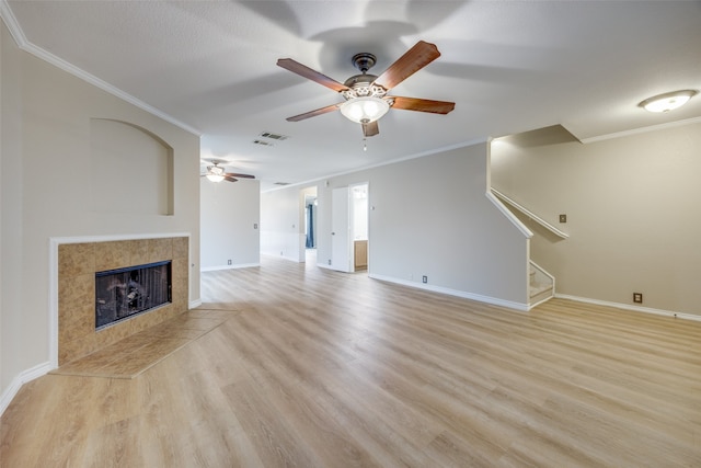 unfurnished living room with ornamental molding, ceiling fan, a tile fireplace, and light hardwood / wood-style floors