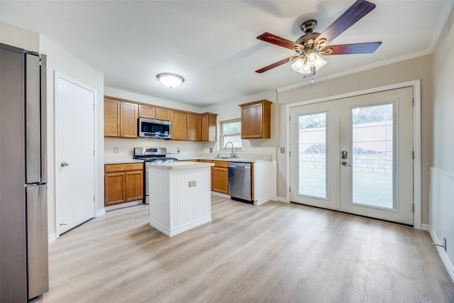 kitchen featuring french doors, crown molding, a kitchen island, light wood-type flooring, and appliances with stainless steel finishes