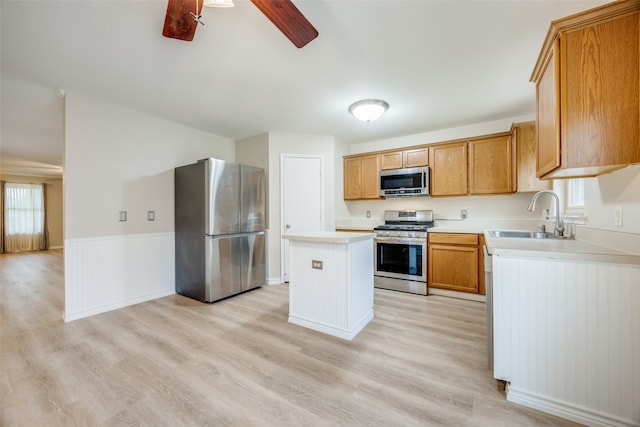 kitchen featuring sink, ceiling fan, a kitchen island, light wood-type flooring, and appliances with stainless steel finishes