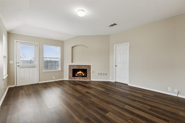 unfurnished living room featuring a tile fireplace, dark wood-type flooring, and lofted ceiling