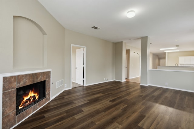 unfurnished living room featuring dark hardwood / wood-style floors and a tiled fireplace