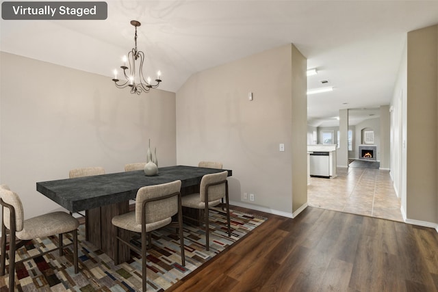 dining space with hardwood / wood-style flooring, lofted ceiling, and a notable chandelier