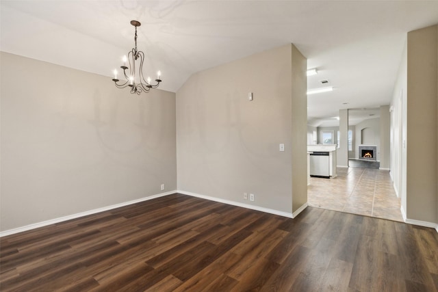 empty room featuring vaulted ceiling, dark hardwood / wood-style floors, and a notable chandelier