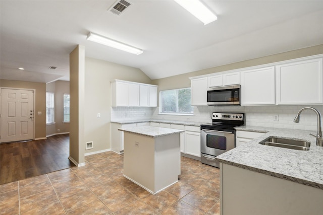 kitchen featuring light stone countertops, appliances with stainless steel finishes, sink, white cabinets, and a center island