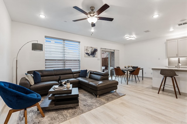 living room featuring light wood-type flooring, sink, and ceiling fan