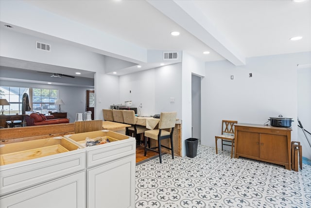 kitchen featuring beamed ceiling and white cabinetry