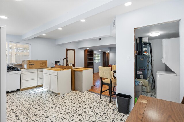 kitchen featuring white cabinets, wooden counters, beam ceiling, and light wood-type flooring