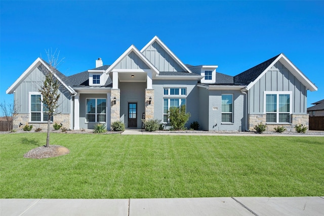 view of front of home featuring stone siding, a front lawn, and board and batten siding