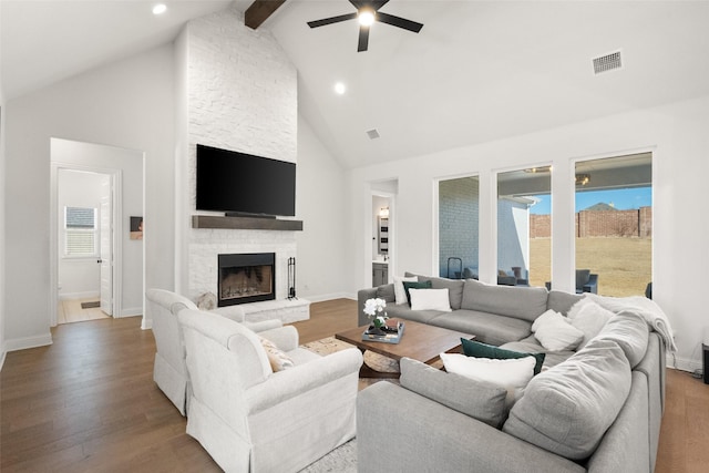 living room with a wealth of natural light, visible vents, a fireplace, and wood finished floors