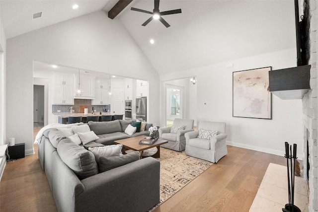 living room featuring ceiling fan, high vaulted ceiling, visible vents, light wood-style floors, and beam ceiling