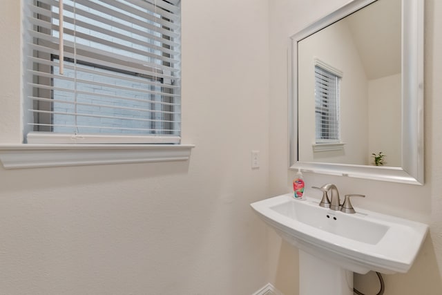 bathroom featuring sink, vaulted ceiling, and a healthy amount of sunlight