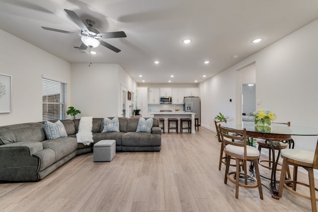 living room with ceiling fan and light hardwood / wood-style flooring