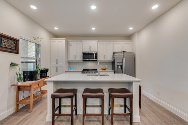 kitchen featuring light hardwood / wood-style floors, white cabinetry, a center island with sink, and appliances with stainless steel finishes