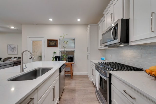 kitchen with white cabinetry, sink, appliances with stainless steel finishes, backsplash, and light wood-type flooring