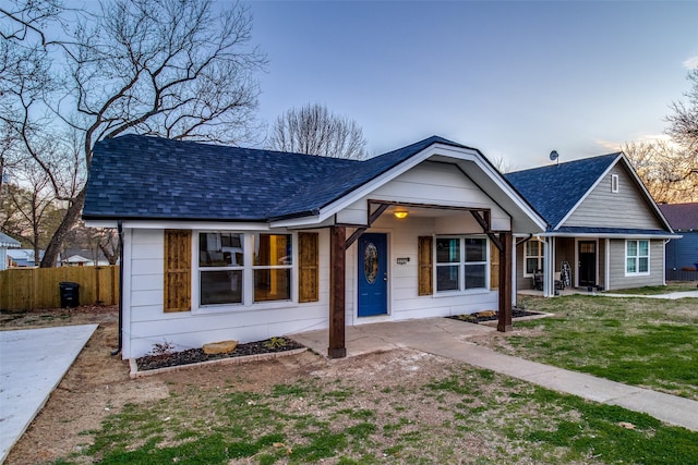 view of front of property with covered porch and a lawn