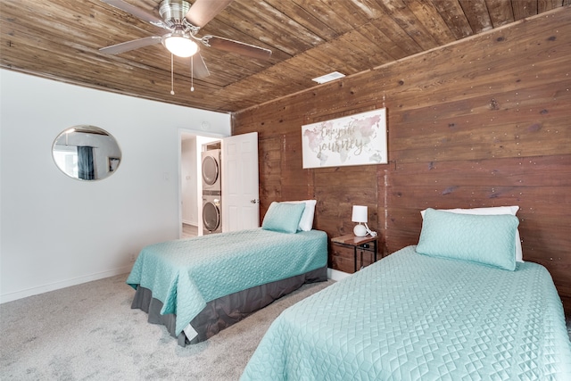 bedroom with wooden ceiling, ceiling fan, carpet, stacked washer and dryer, and wooden walls