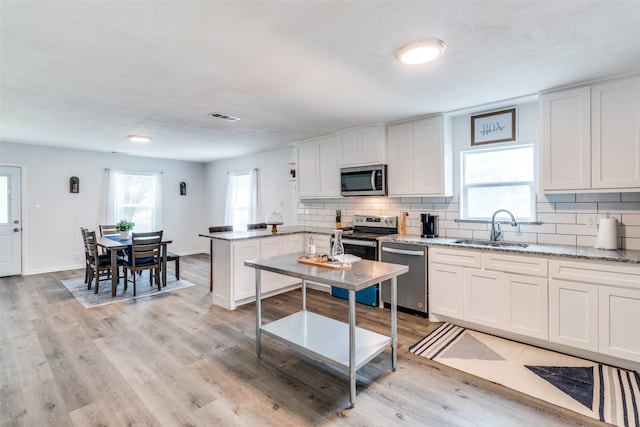 kitchen with plenty of natural light, white cabinetry, sink, and stainless steel appliances