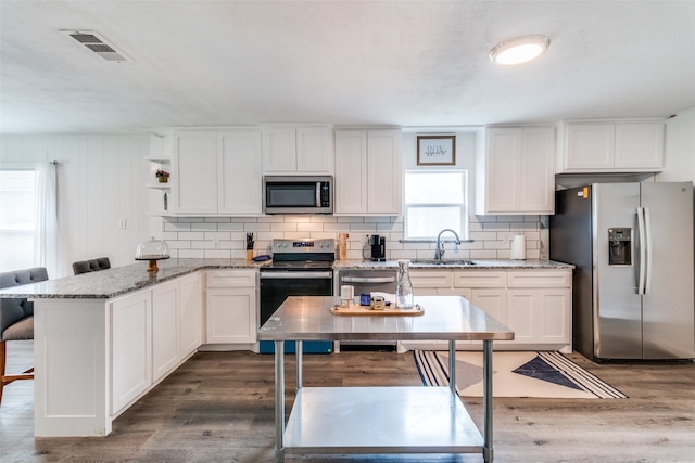 kitchen featuring white cabinets, sink, dark hardwood / wood-style floors, appliances with stainless steel finishes, and dark stone countertops