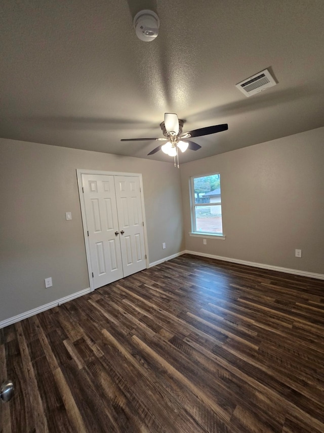 unfurnished bedroom featuring a textured ceiling, ceiling fan, dark hardwood / wood-style floors, and a closet