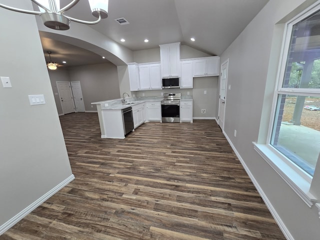 kitchen with kitchen peninsula, appliances with stainless steel finishes, lofted ceiling, white cabinets, and dark wood-type flooring