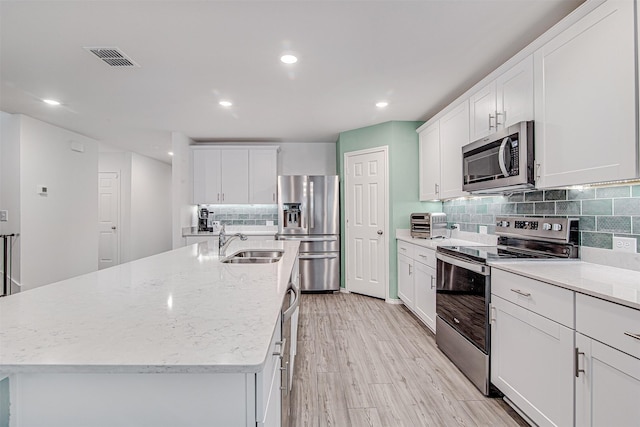 kitchen with white cabinetry, a center island with sink, stainless steel appliances, and sink