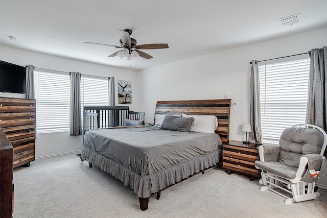 carpeted bedroom featuring multiple windows and ceiling fan