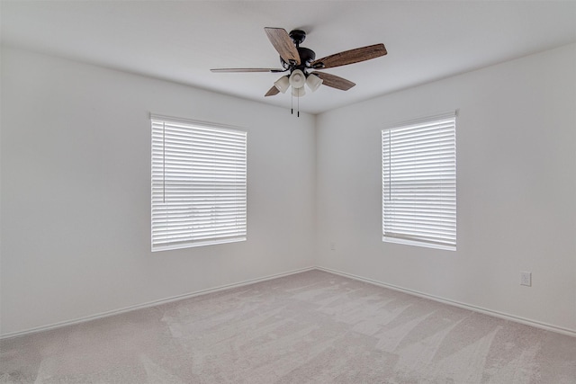 carpeted spare room featuring plenty of natural light and ceiling fan