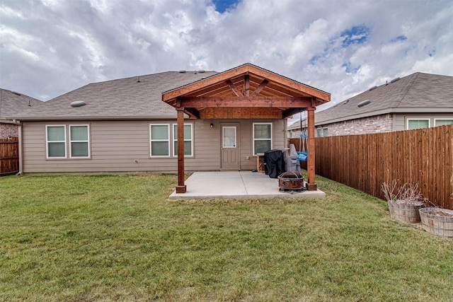 back of house featuring a yard, a patio, and a fire pit