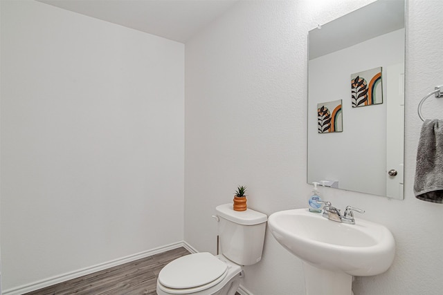 bathroom with toilet, wood-type flooring, and sink