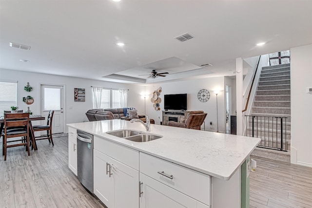 kitchen featuring dishwasher, a kitchen island with sink, white cabinets, a raised ceiling, and sink