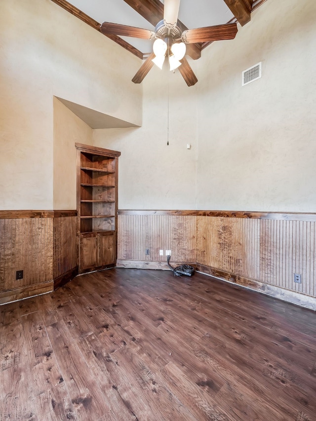 empty room with a towering ceiling, wood-type flooring, and wooden walls