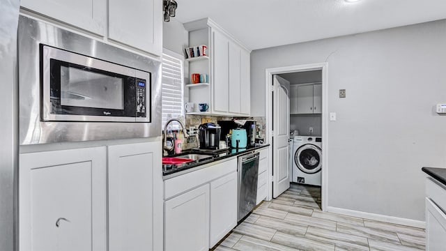 kitchen featuring stainless steel appliances, light hardwood / wood-style floors, sink, washer / clothes dryer, and white cabinets