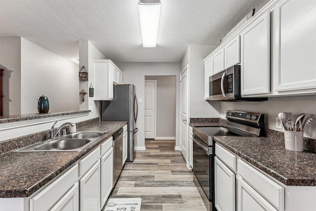 kitchen featuring light hardwood / wood-style floors, white cabinetry, sink, appliances with stainless steel finishes, and a textured ceiling