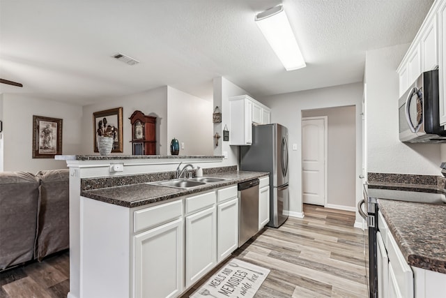 kitchen featuring kitchen peninsula, white cabinetry, light hardwood / wood-style flooring, and appliances with stainless steel finishes