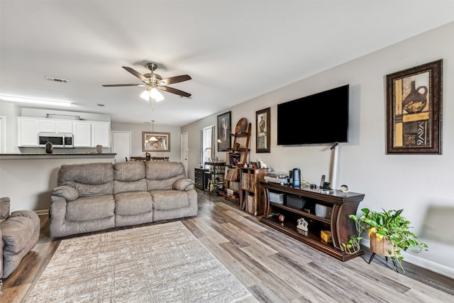 living room with light hardwood / wood-style floors and ceiling fan