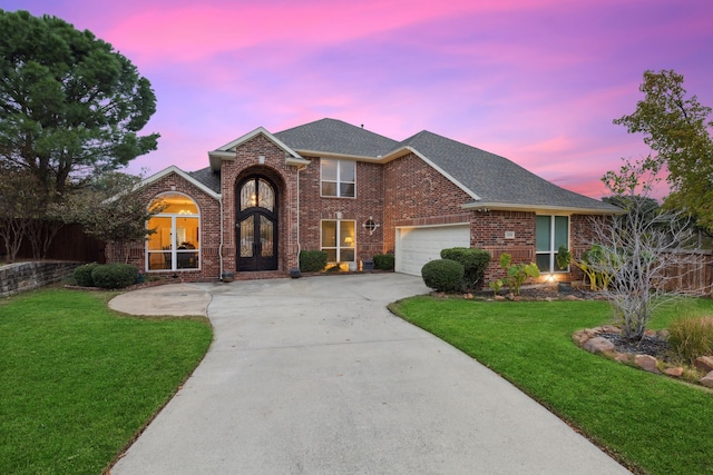 view of front of house featuring french doors, a garage, and a lawn