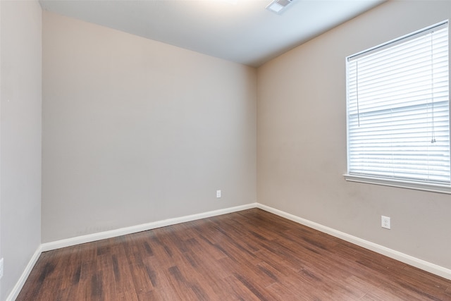 spare room featuring plenty of natural light and dark wood-type flooring