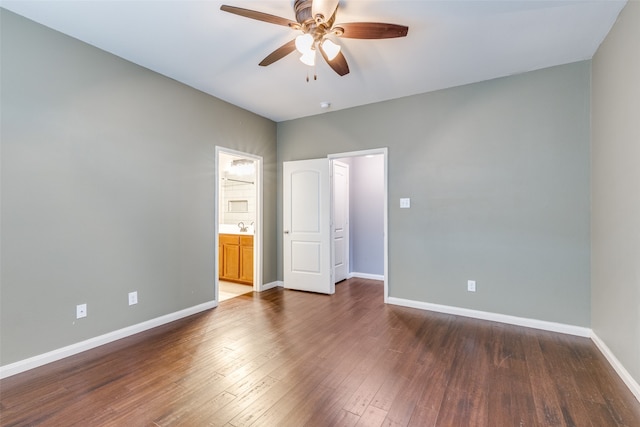 unfurnished bedroom featuring dark wood-type flooring, sink, ceiling fan, and ensuite bathroom