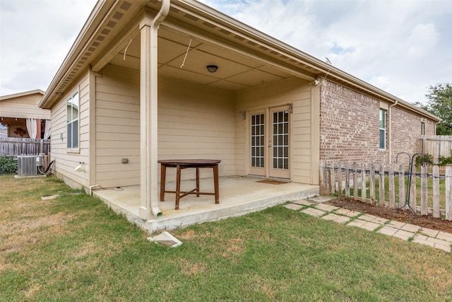 back of house featuring cooling unit, a lawn, and a patio