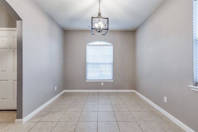 spare room with a chandelier and light tile patterned flooring