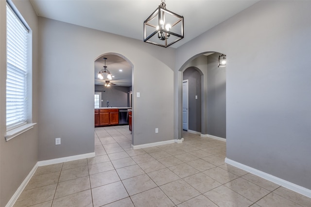 unfurnished dining area featuring ceiling fan with notable chandelier and light tile patterned floors