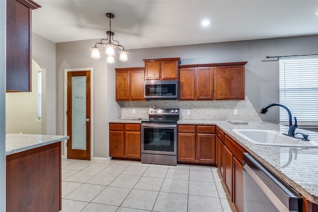 kitchen featuring stainless steel appliances, hanging light fixtures, sink, and light stone counters