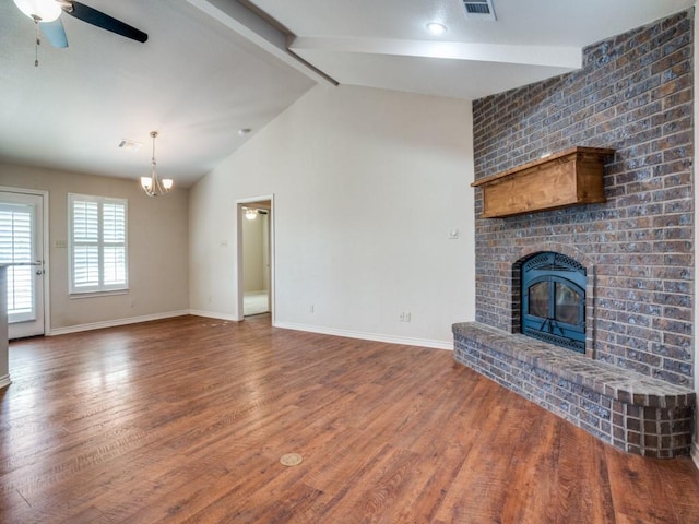 unfurnished living room with vaulted ceiling with beams, ceiling fan with notable chandelier, a fireplace, and hardwood / wood-style flooring