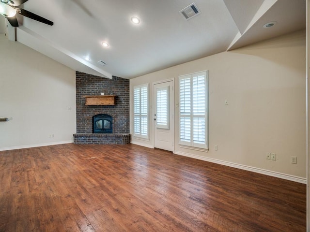 unfurnished living room featuring dark wood-type flooring, ceiling fan, lofted ceiling, and a brick fireplace