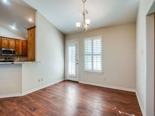 interior space featuring a chandelier, vaulted ceiling, hanging light fixtures, dark hardwood / wood-style flooring, and stainless steel appliances